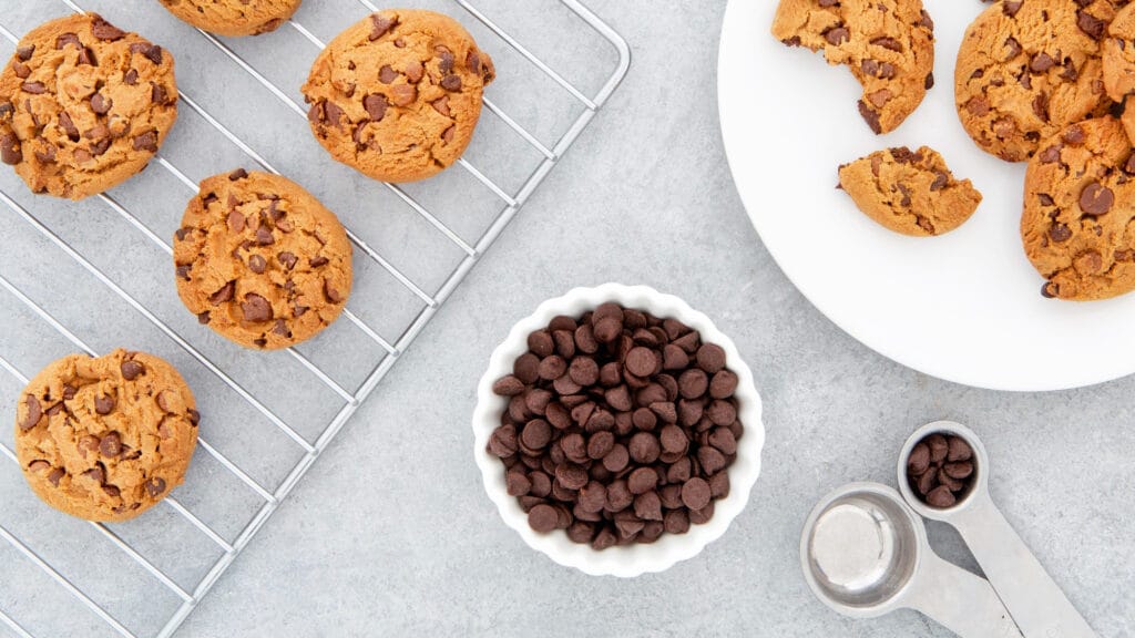 Freshly baked cookies made with the Nestle cookie recipe, displayed on a cooling rack with chocolate chips.