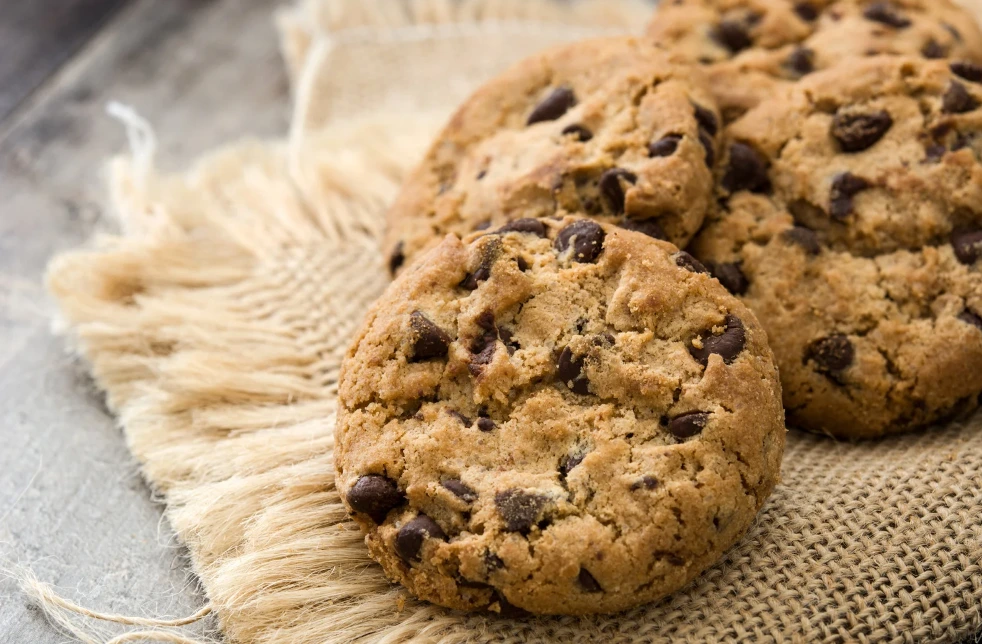 Golden-brown Nestle chocolate chip cookies on a cooling rack, with a glass of milk in the background.