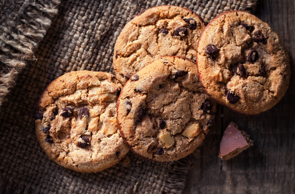 Golden-brown Nestle chocolate chip cookies on a cooling rack, with a glass of milk in the background.