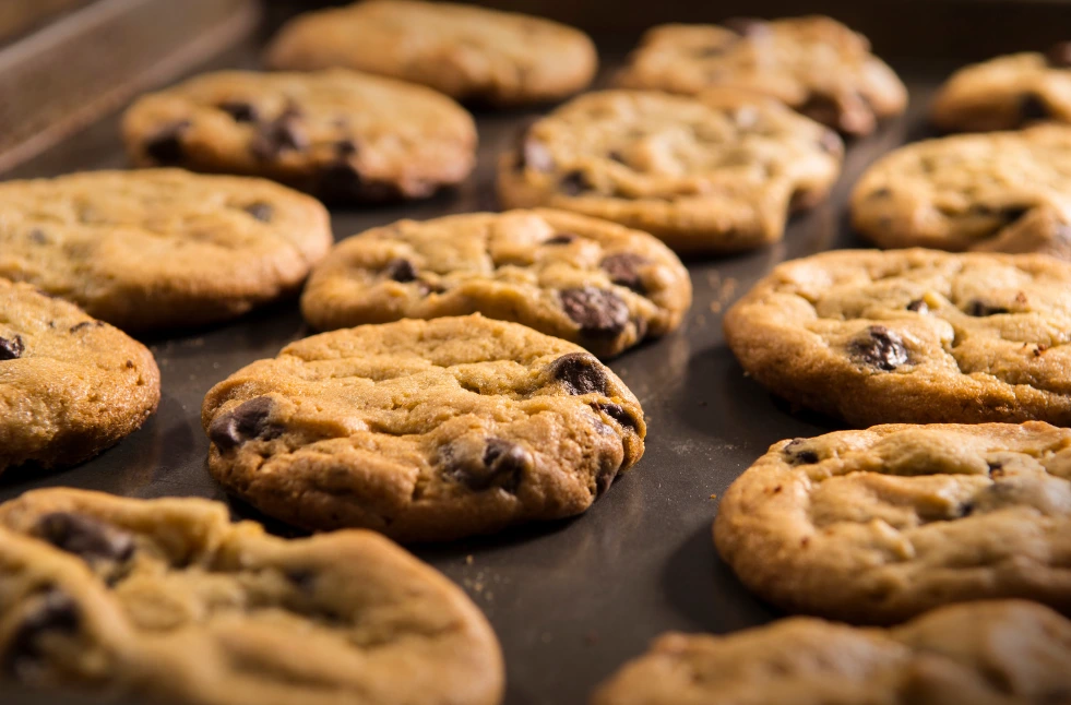 Golden-brown Nestle chocolate chip cookies on a cooling rack, with a glass of milk in the background.