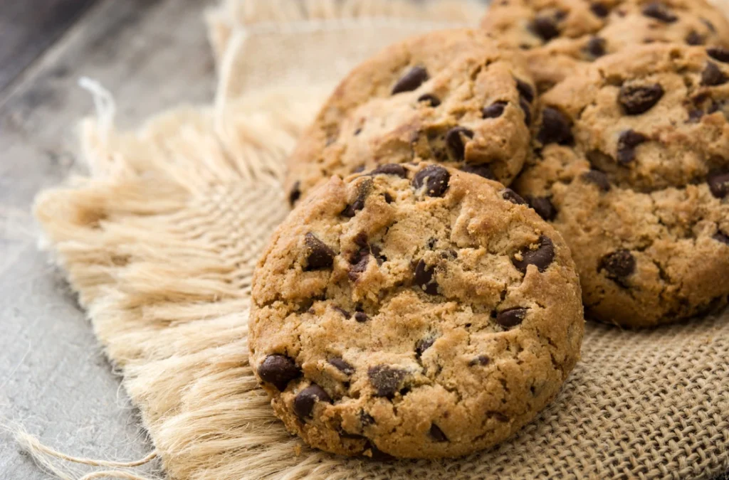 Raw Nestlé cookie dough alongside freshly baked cookies on a rustic wooden table.