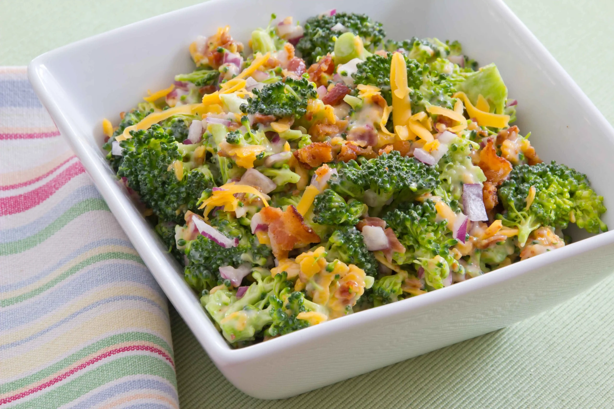 A vibrant bowl of broccoli salad from Chicken Salad Chick, showcasing fresh ingredients like broccoli, bacon, and cheese.