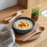 A comforting bowl of creamy rice porridge on a wooden kitchen counter.