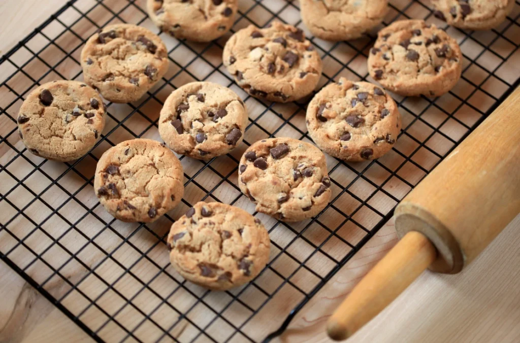 A freshly baked batch of chocolate chip cookies made using a recipe without brown sugar, placed on a wooden table.