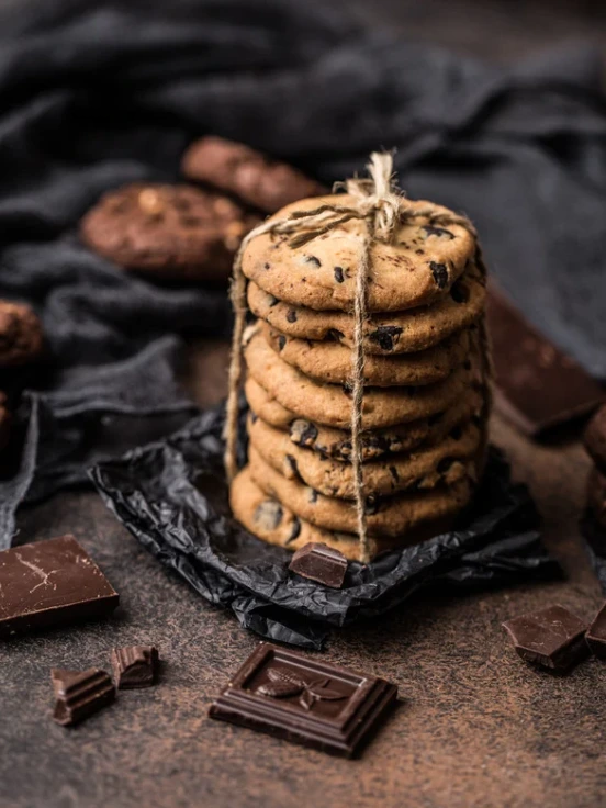 A freshly baked batch of chocolate chip cookies made using a recipe without brown sugar, placed on a wooden table.