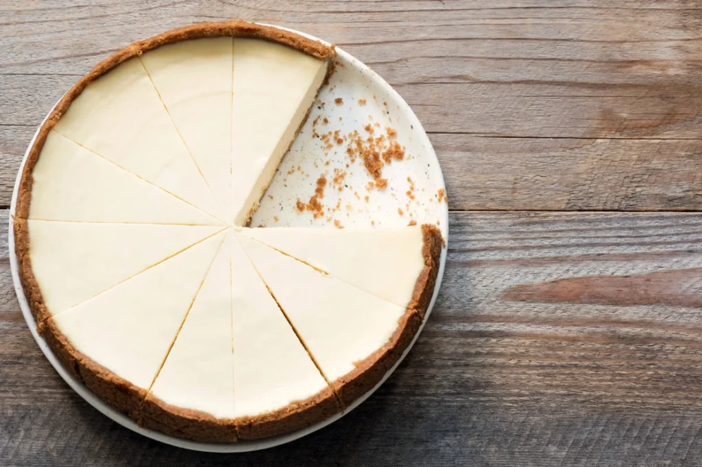 A creamy, classic cheesecake with a golden crust and fresh berry topping on a white plate.