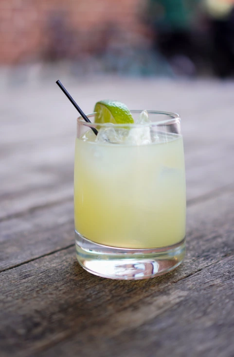 A refreshing skinny margarita with lime garnish and a salt rim on a wooden table.