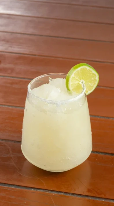 A refreshing skinny margarita with lime garnish and a salt rim on a wooden table.