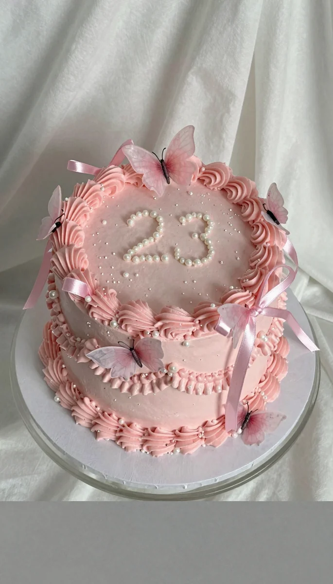 Save this An elegant 23rd birthday cake in pale pink with intricate white pearl and frosting decorations, on a glass stand with a blank dark grey section at the bottom. on Pinterest
