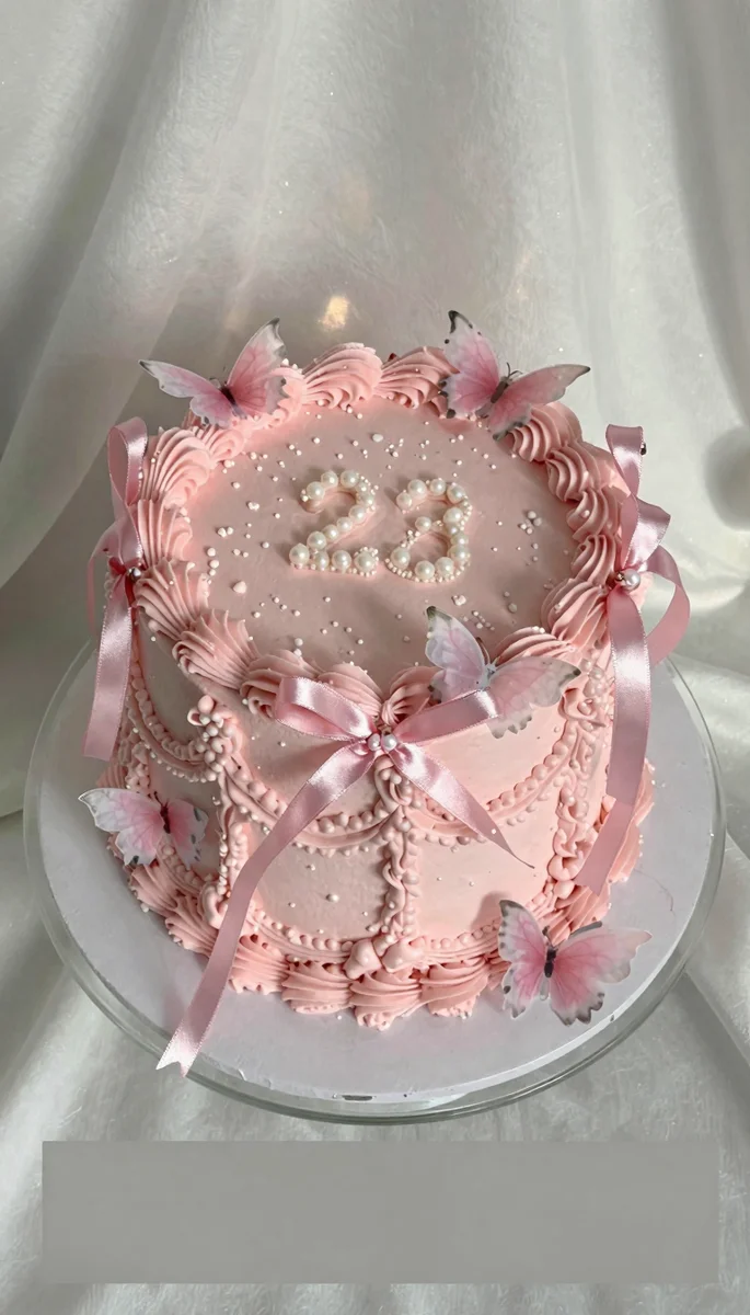 Save this A photorealistic pink birthday cake featuring delicate piping, bows, and pearls, displayed on a cake stand against a white background. on Pinterest